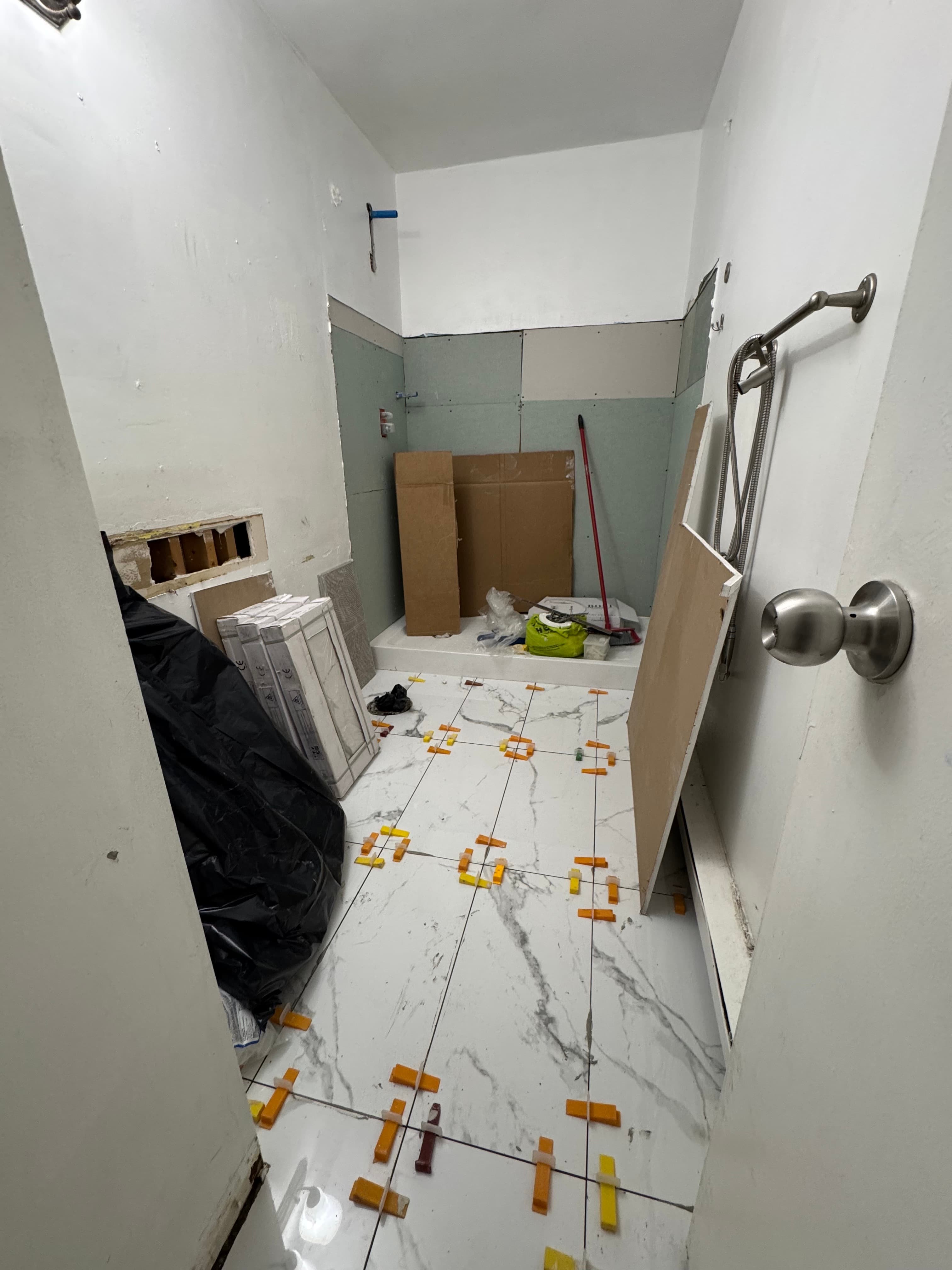 Bathroom renovation showing wall preparation, a new shower base, and floor tile installation