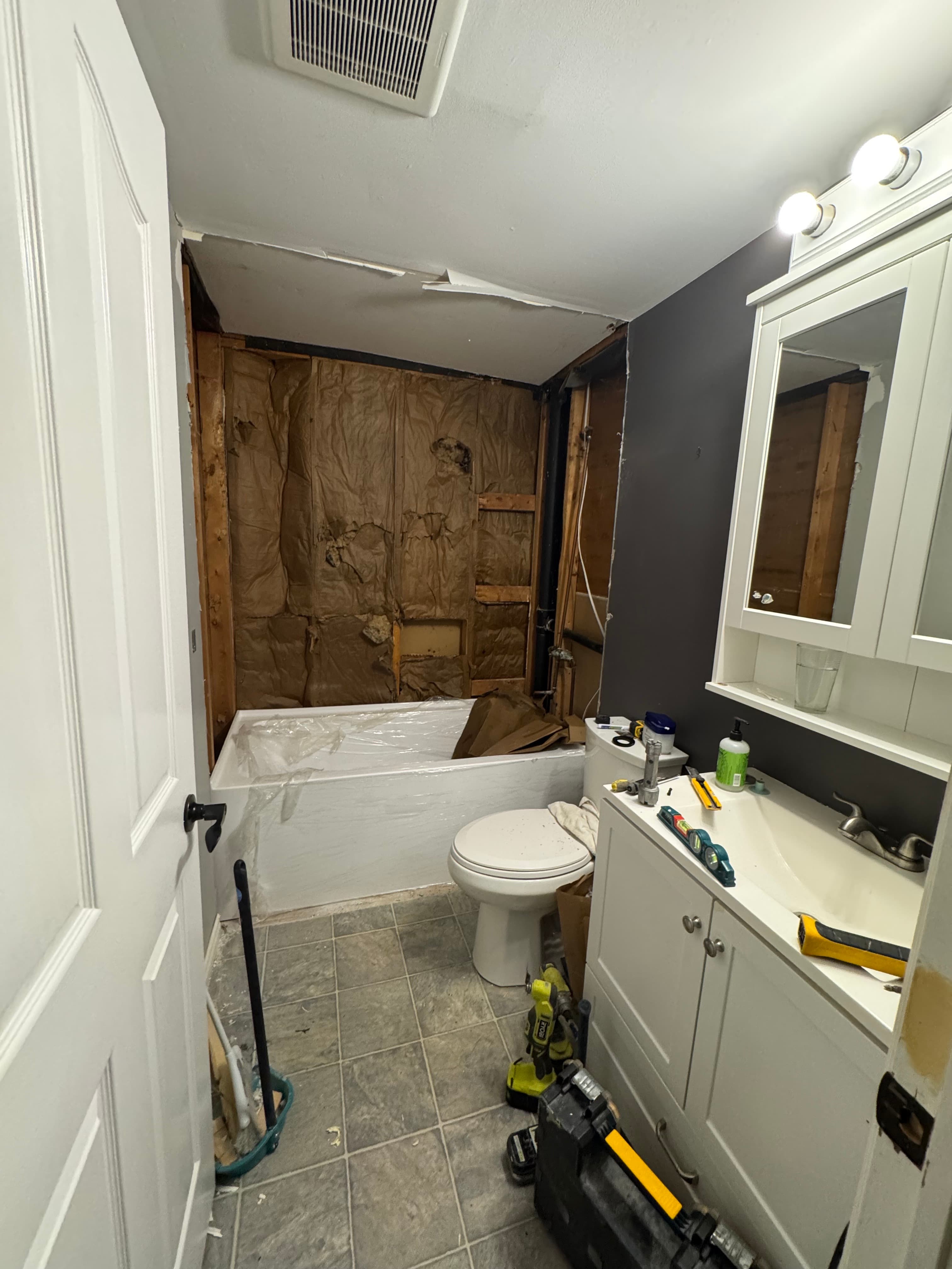 Bathtub surround opened to framing and insulation during a bathroom renovation